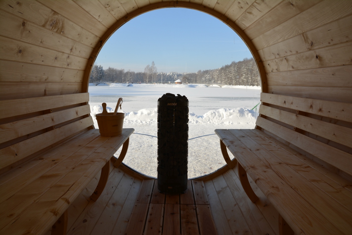 Widok ze środka sauny na ośnieżony zbiornik wodny.